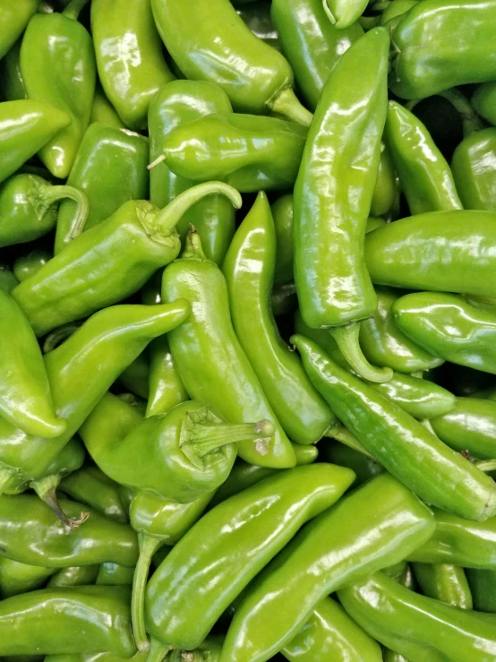 a bunch of green peppers are piled up together