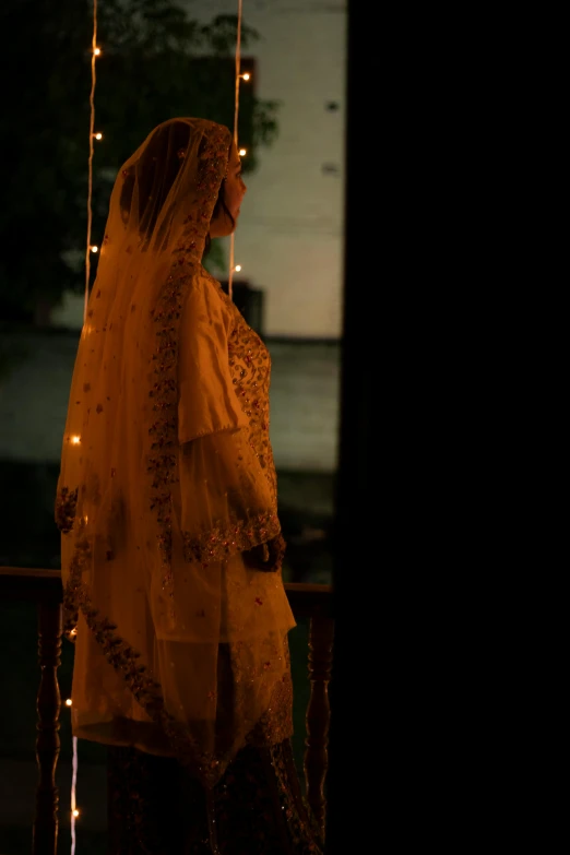 a woman standing on a porch next to a string of lights