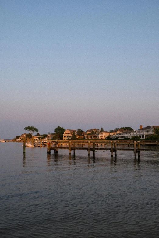 a long bridge is spanning the water with houses