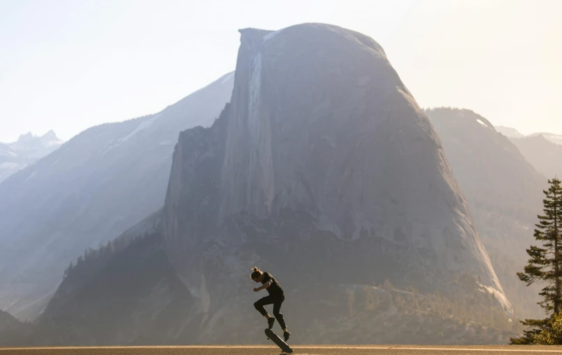 man doing a jumping trick by tall mountains