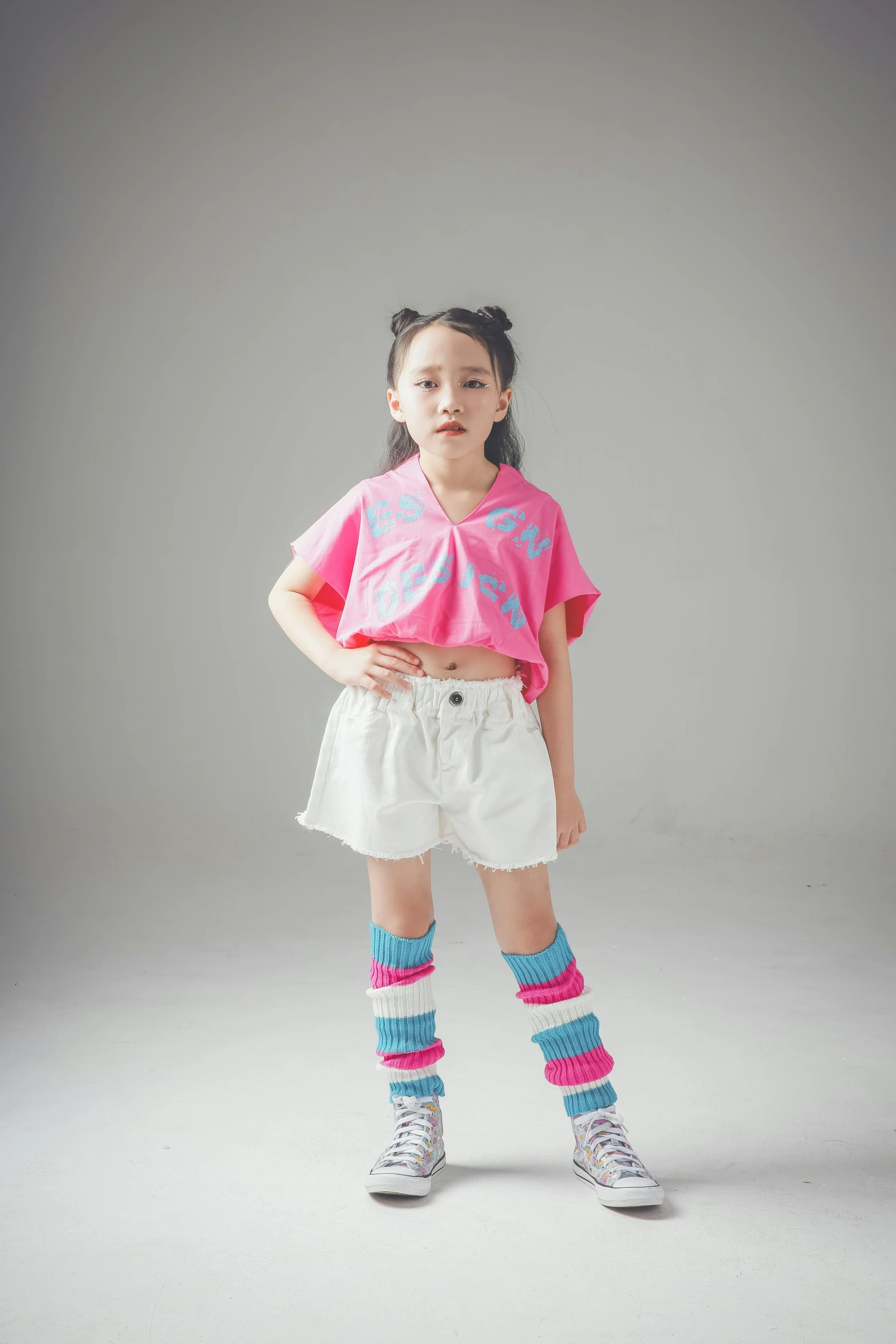 a little girl in pink top and white shorts with blue socks