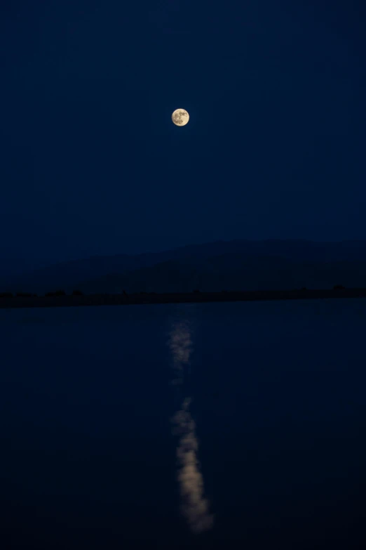 a moon that is rising over a body of water