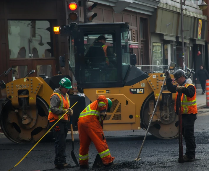 a man in orange safety gear using a large street sweeper