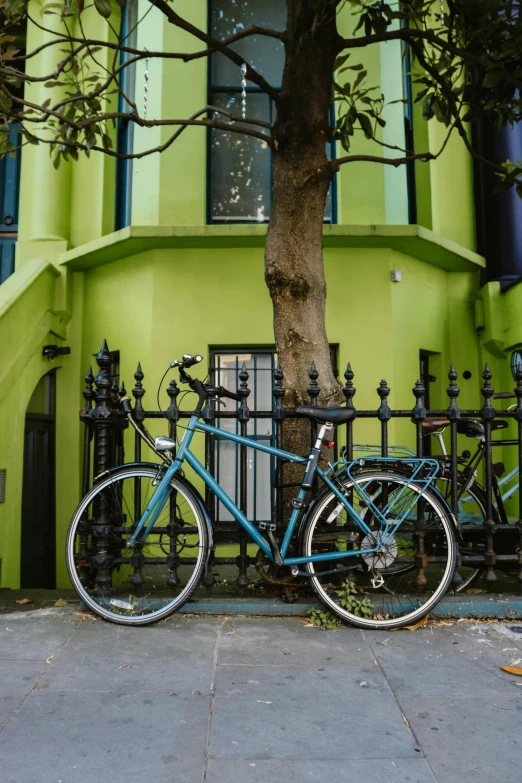 the bicycle is parked beside the fence of the building