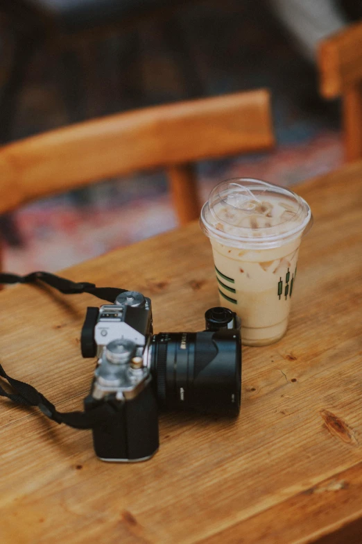 a camera and iced coffee on a wooden table