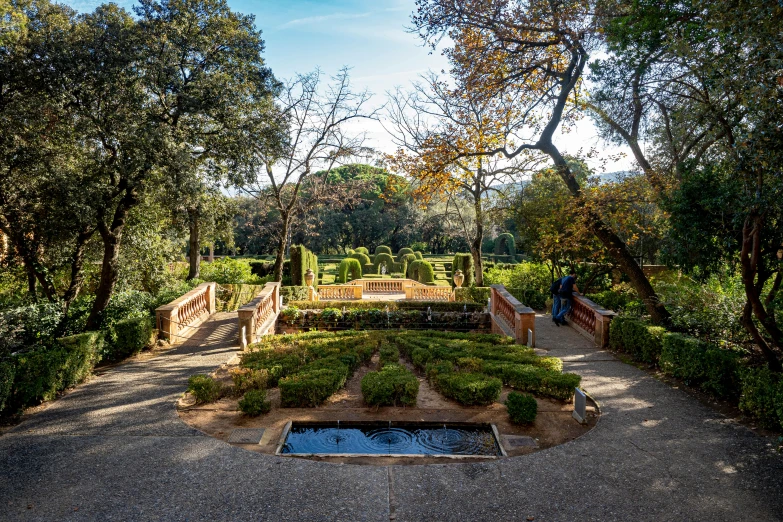 a man stands by the formal garden, overlooking the river