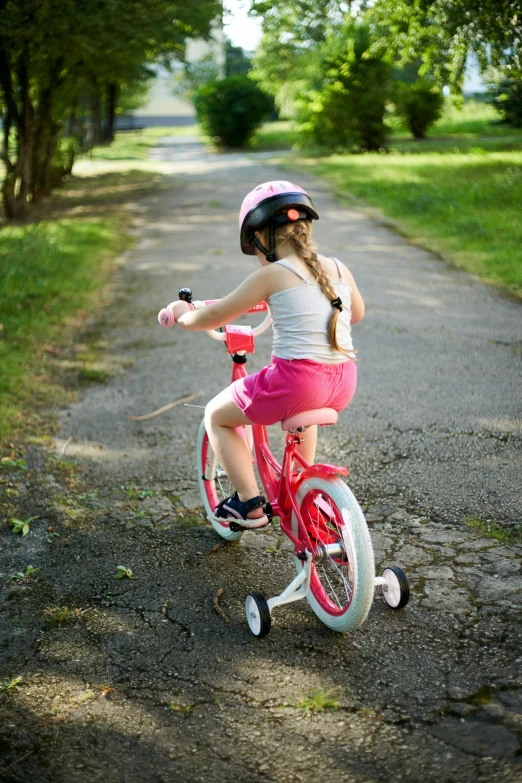 a girl in pink riding on a red bicycle
