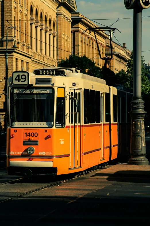 an orange and white passenger train is near a tall building