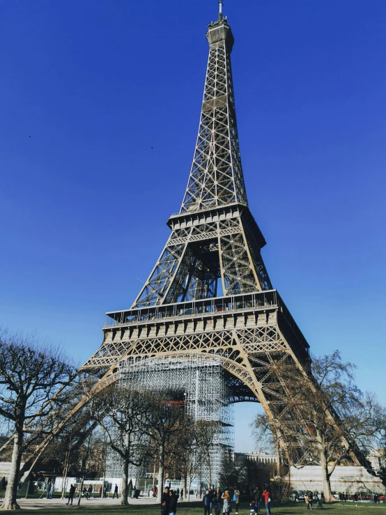 people walking by the side of the eiffel tower