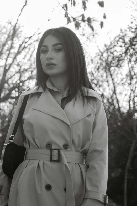 a woman in a trench coat walks away from a park