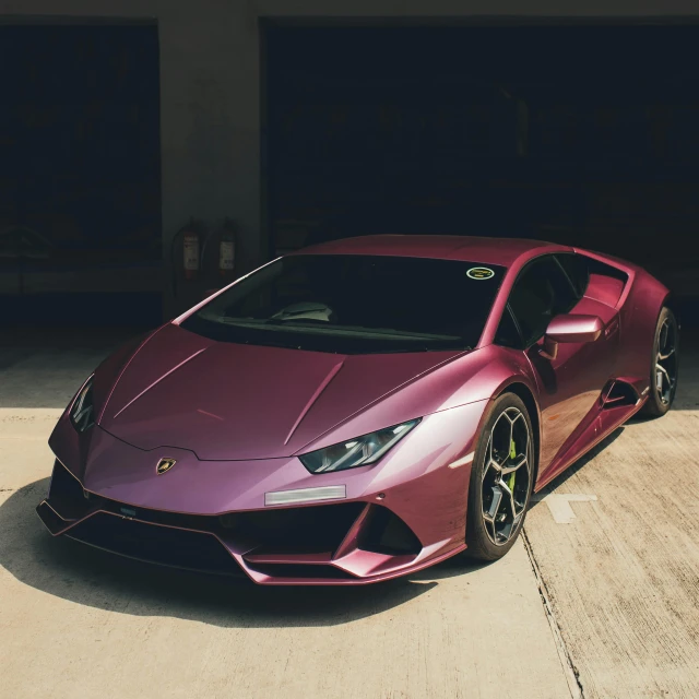 a shiny pink lamb car in the middle of a driveway