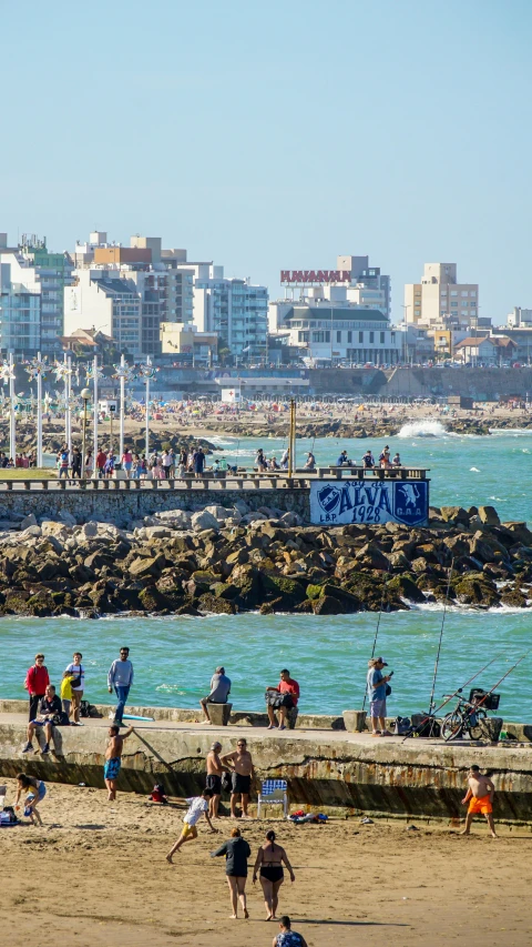 group of people on the beach with buildings in the background