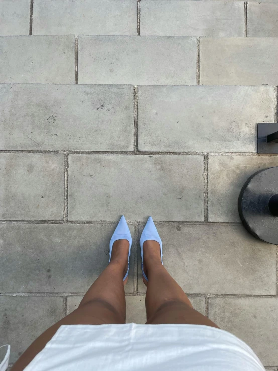 someone's feet in blue shoes on a concrete surface