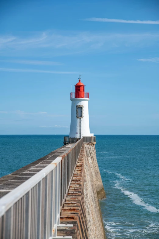 a light house on a jetty near the ocean