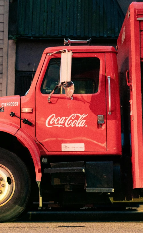 a red coca cola truck sitting next to a building