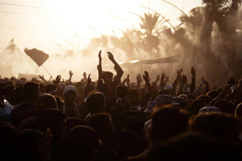 a crowd of people with hands up and arms in the air