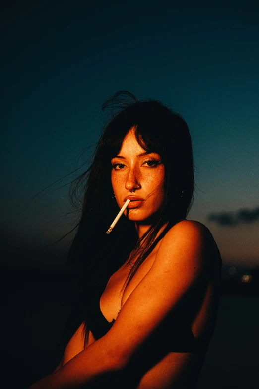 woman in bathing suit smoking cigarette at dusk