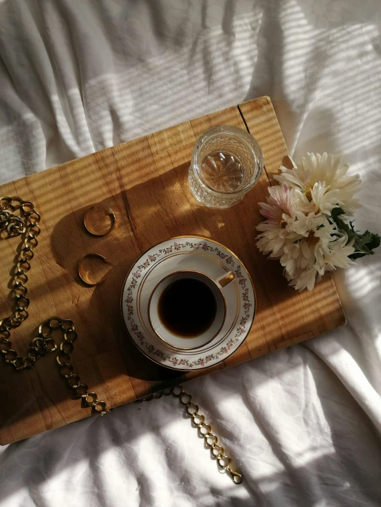 a coffee cup and some gold chains on top of a bed