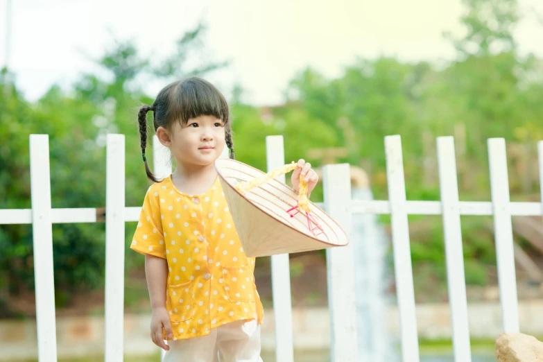 a little girl wearing white pants and a yellow shirt holding a surfboard