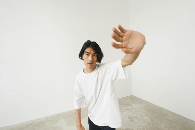 a man standing in front of a white wall holding a peace sign