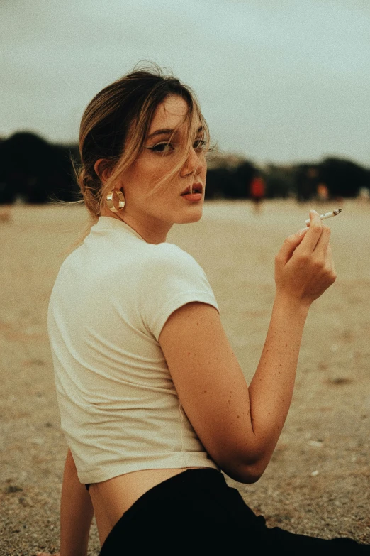 a woman smoking in the open near the ocean