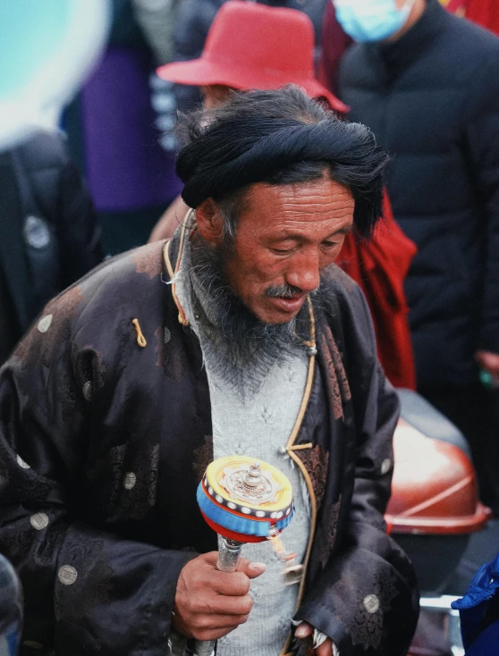 a man with a long beard and beard standing holding an item in his hand