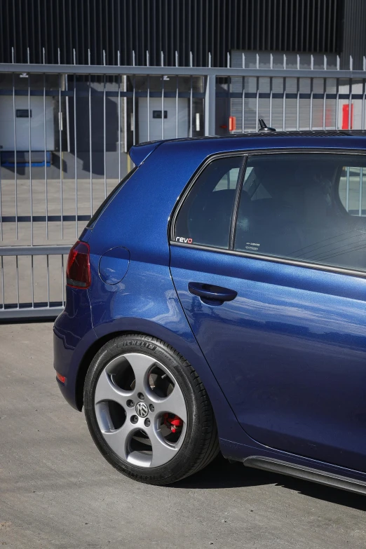 the blue car is parked near a gate