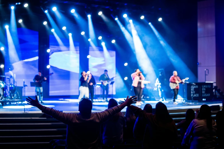 a crowd is standing on stage to look at the band playing