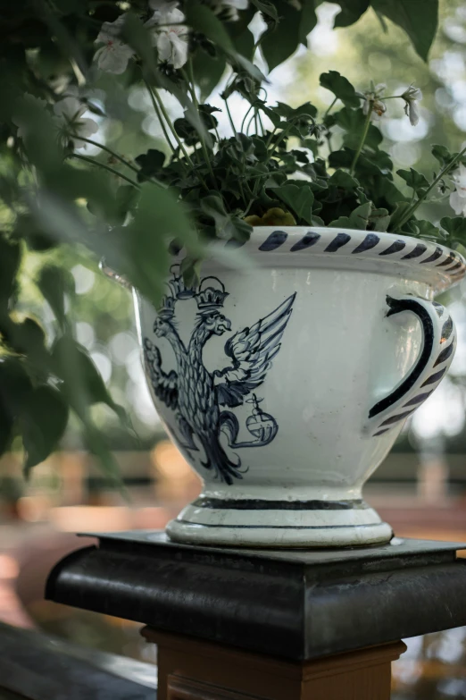 a white vase with a winged eagle sits on a pedestal