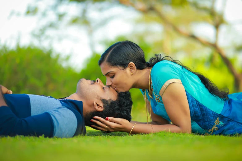 two people laying in the grass with one touching the lips