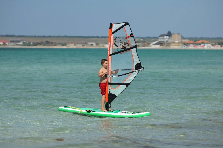 a boy windsurfs through the blue water on a sunny day