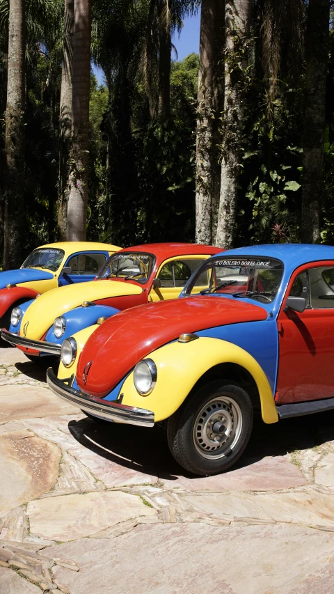 an old volkswagen beetle painted different colors parked in the shade