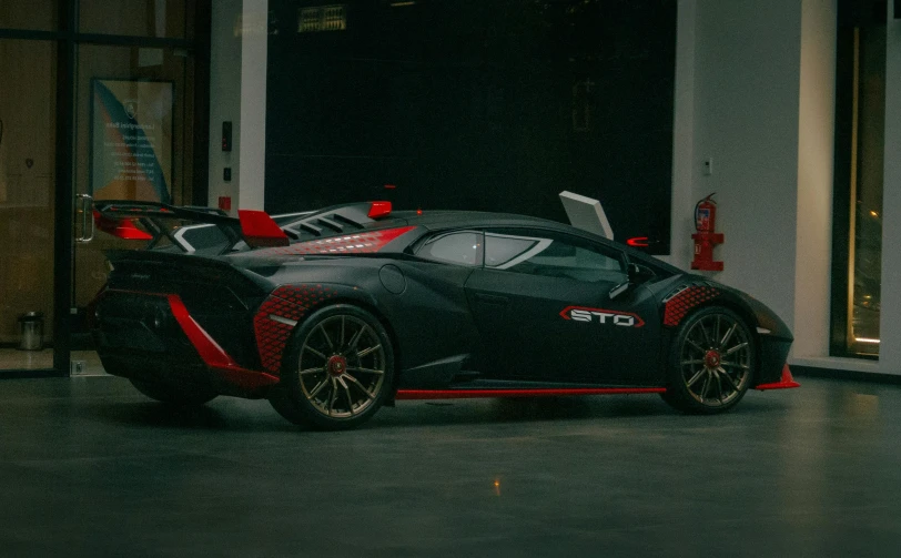 the black sports car sits parked outside of a building