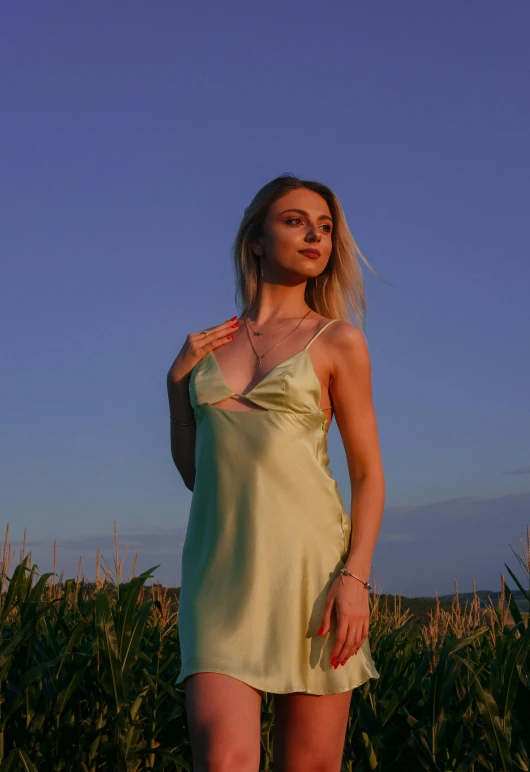 a woman standing in a corn field and holding a cell phone to her ear