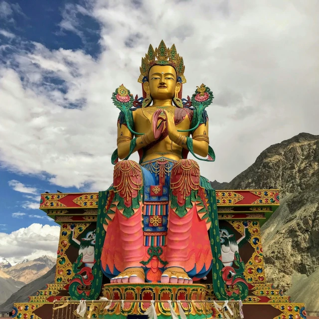 a statue of a buddha sitting in front of some mountains
