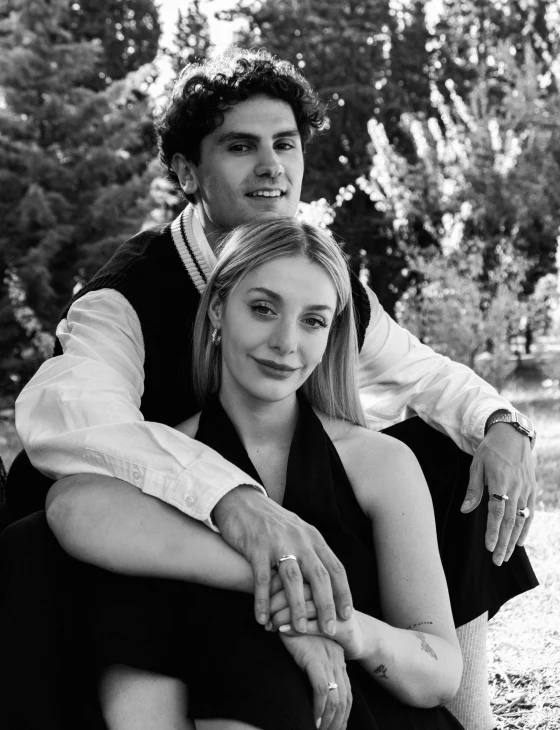 a man is leaning on a pretty young woman in the grass