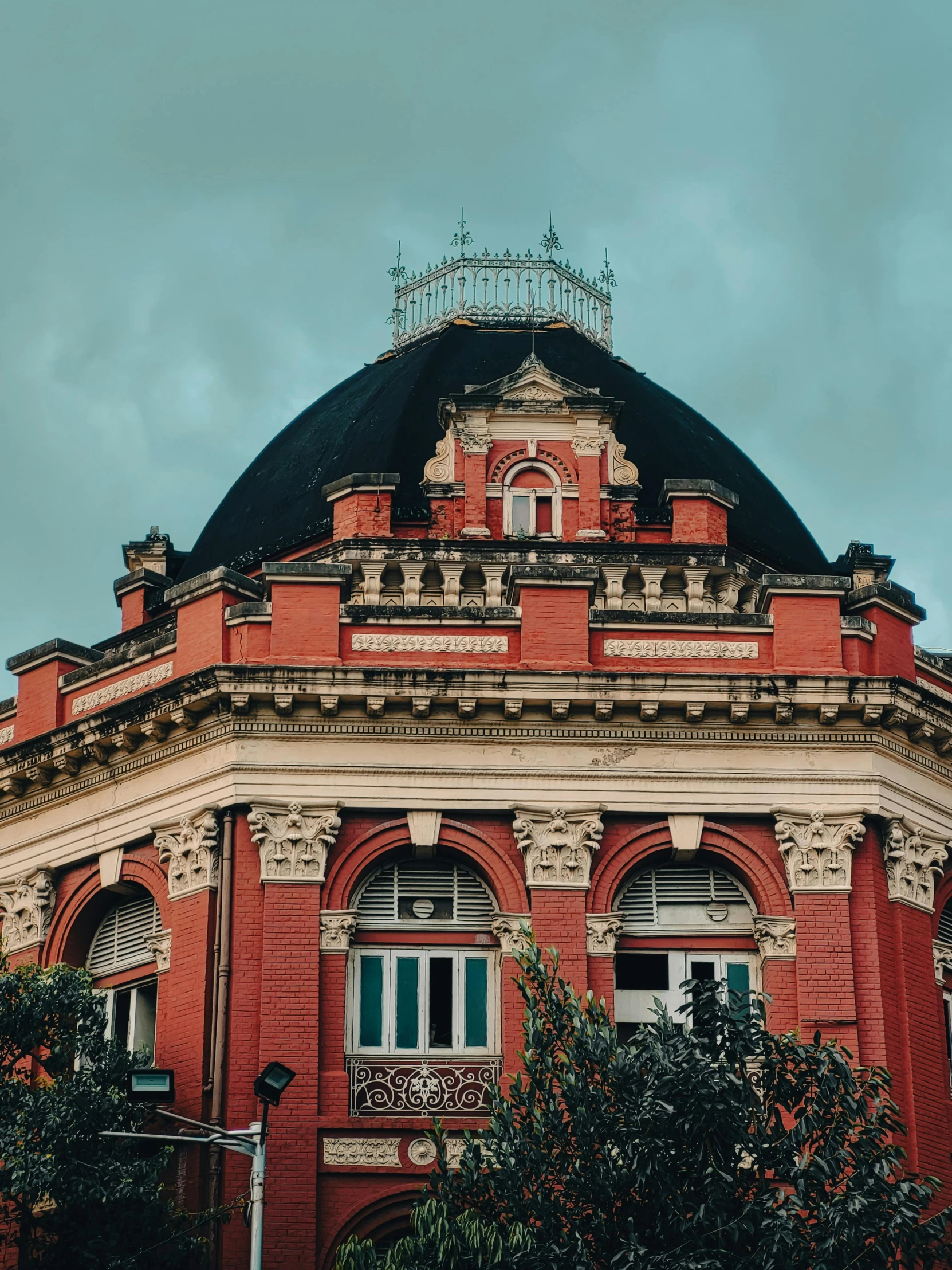 a large red building with some green bushes