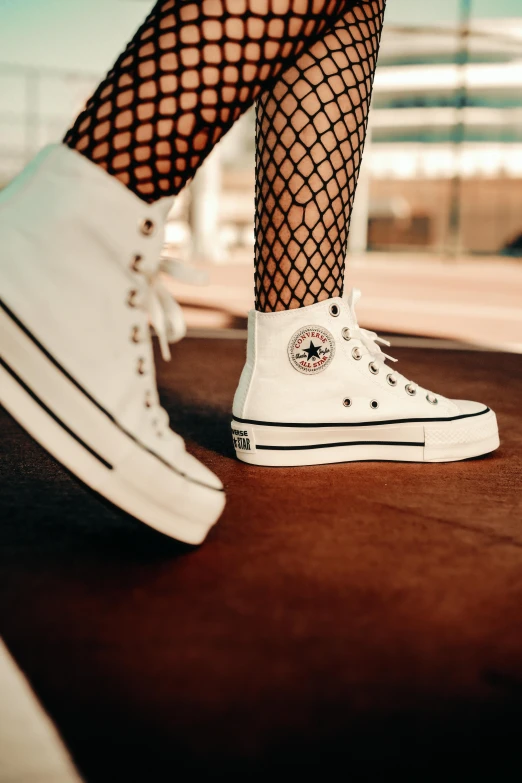 a woman wearing fishnet stockings and white tennis shoes