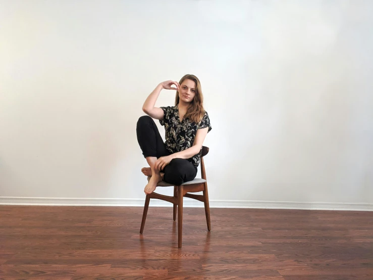 a woman sitting on top of a wooden chair