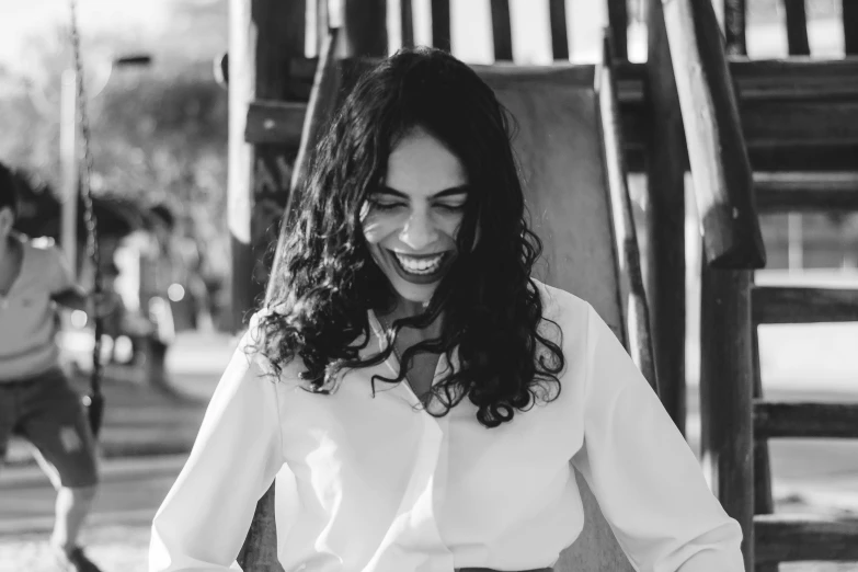 a woman smiling while riding a swing set