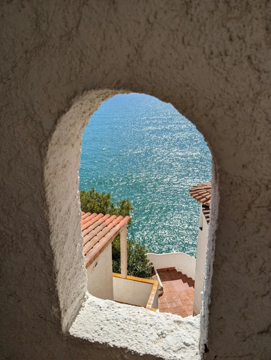 a small window to a building overlooks the ocean