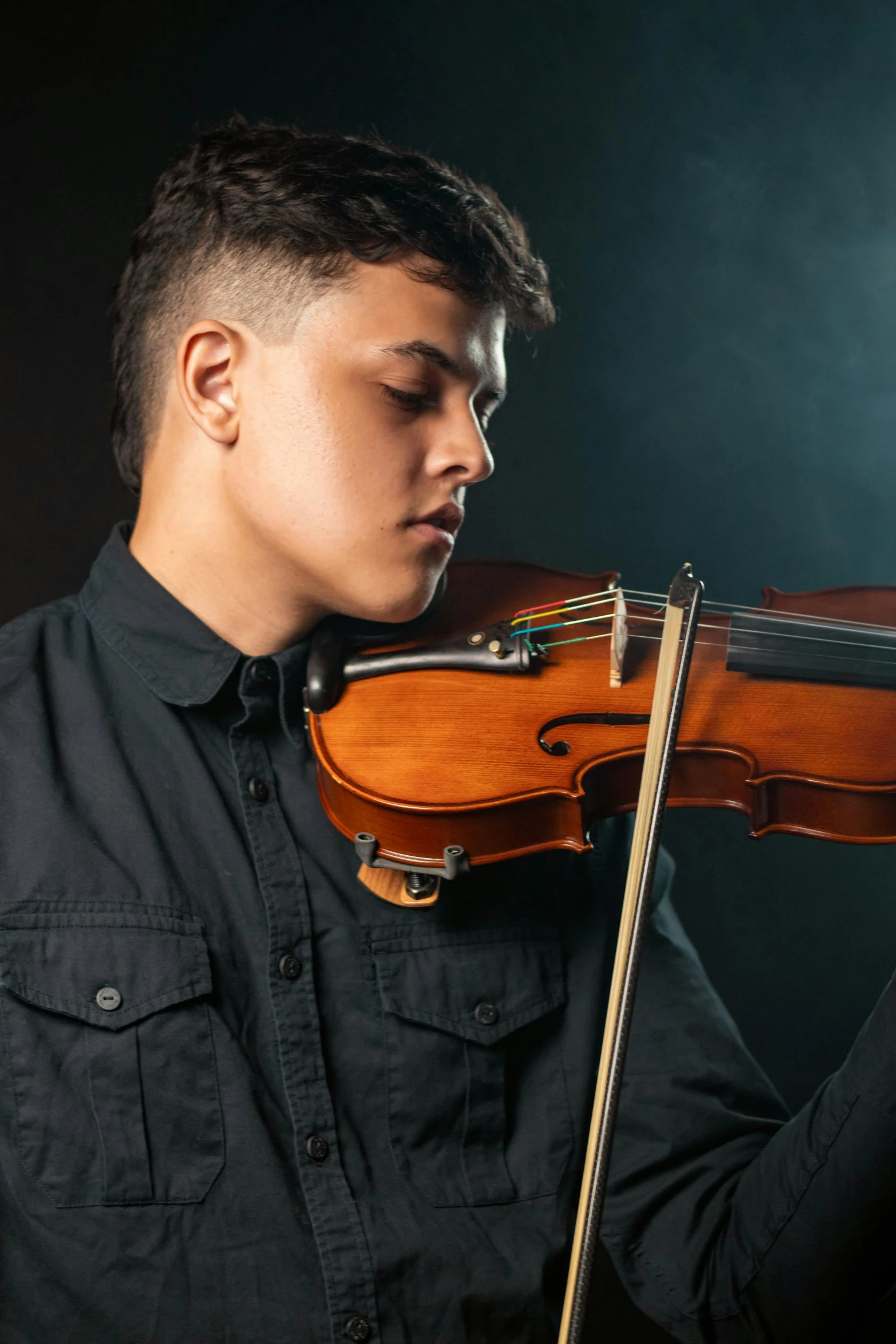 a man plays the violin on a dark stage