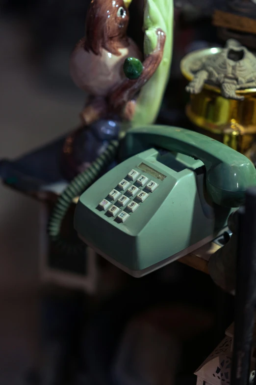 green telephone with man holding it up against a table