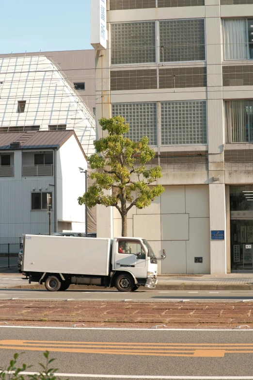 a white truck parked next to a tree in front of buildings