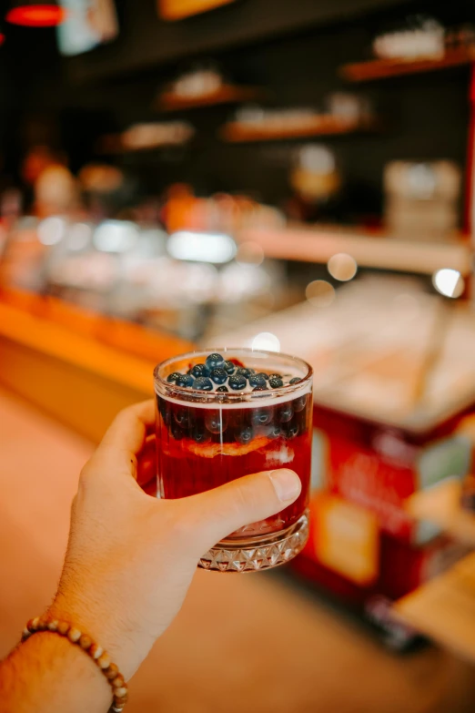 a person holding a drink in front of a counter