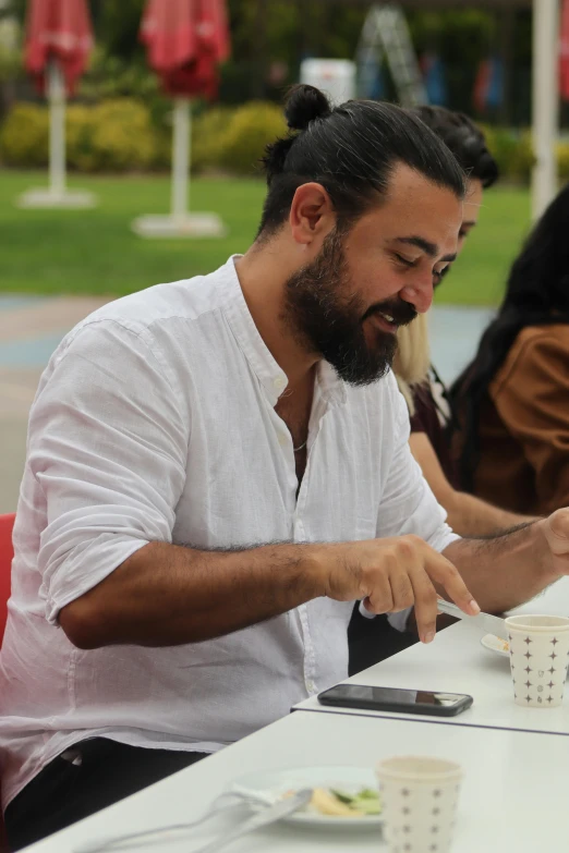 a man with a beard eating food while sitting at a table