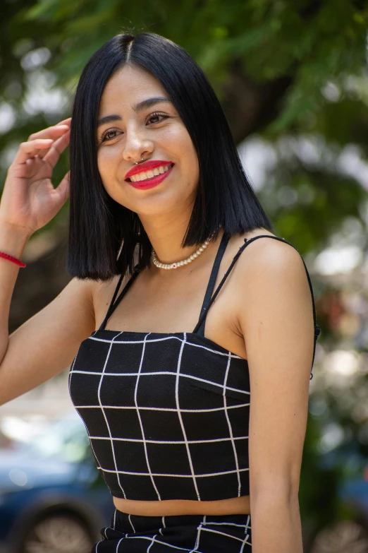 a woman is standing outside with her arms behind her head