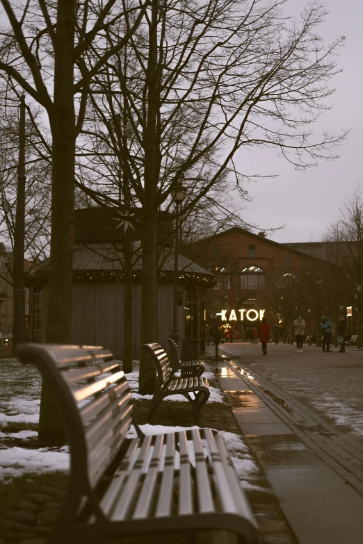 a bench is on the sidewalk in the snow