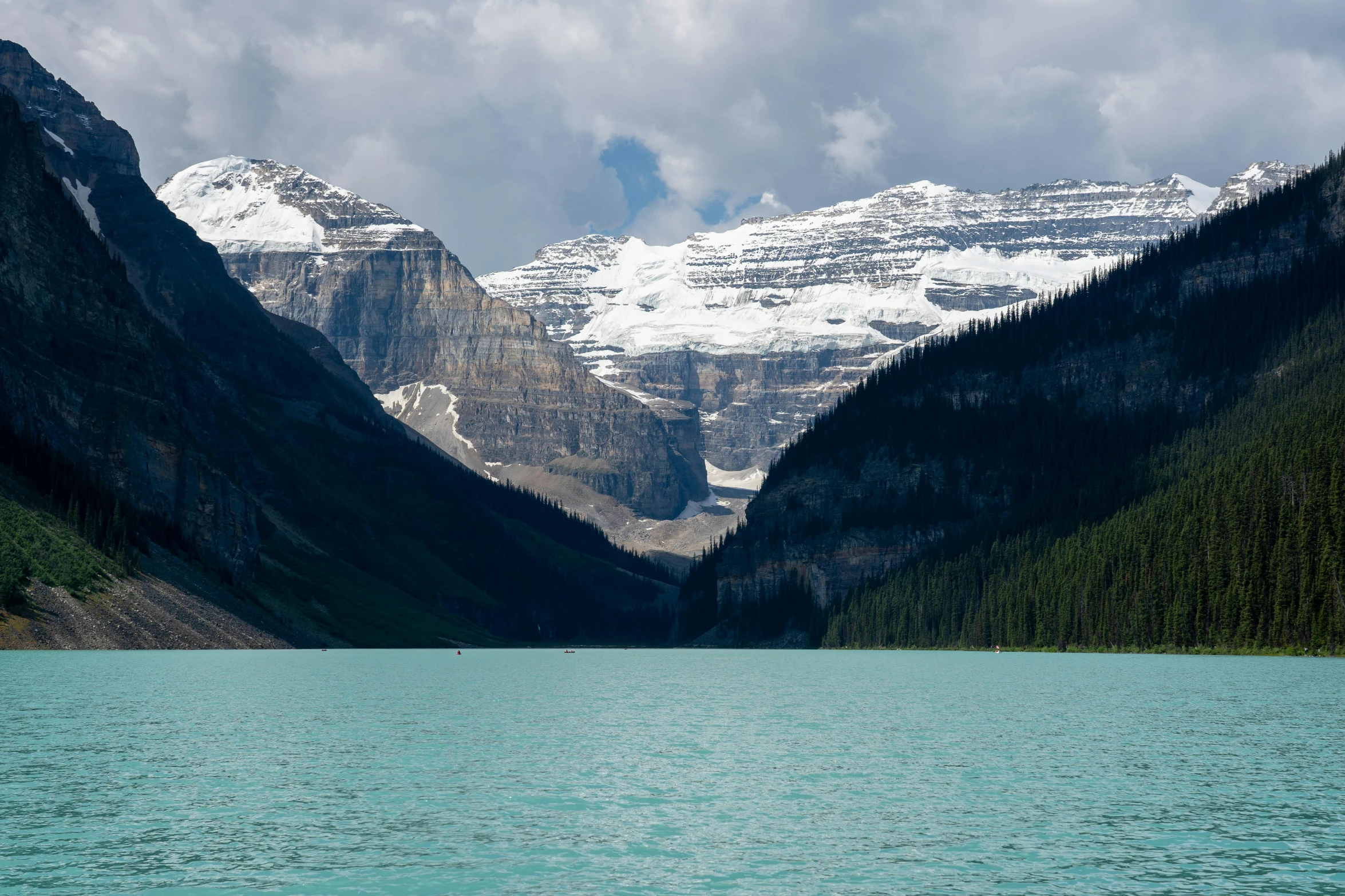 the mountains are snow covered as they rise over the water