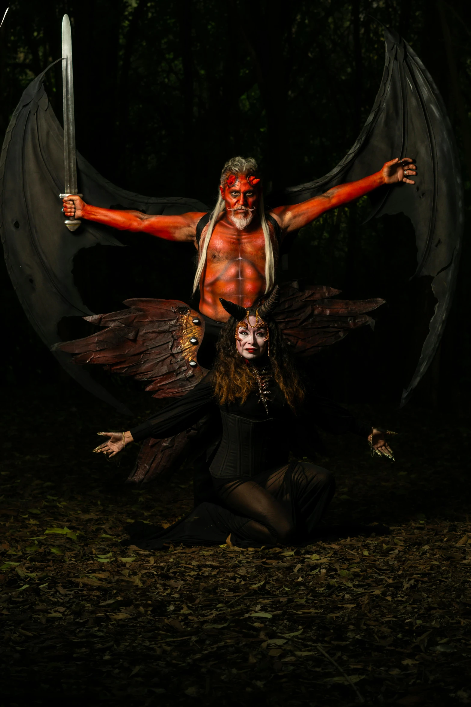 two men, one in red, the other in white, holding hands while standing next to each other in the woods